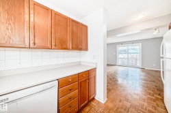 The kitchen features wood cabinetry, a white countertop, and a white tile backsplash - 