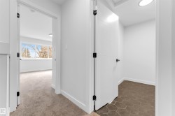Hallway featuring crisp white walls, contemporary black hardware, and recessed lighting - 