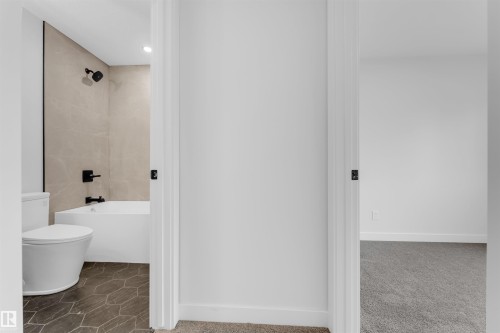 Contemporary bathroom featuring a tub/shower combination with matte black fixtures, full-height wall tiling, and hexagonal floor tiles - 7934 77 Avenue, Edmonton, AB - Indoor Photo Showing Bathroom