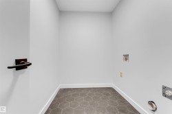 Utility area featuring hexagonal floor tiles, white baseboards, and a dark wood-finish towel bar - 