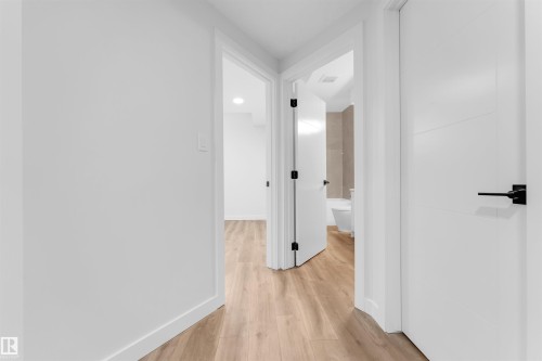 Hallway with wood-finish flooring and bright white walls - 7934 77 Avenue, Edmonton, AB - Indoor Photo Showing Other Room
