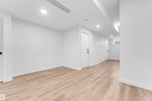 Spacious interior featuring light wood-finish flooring, white walls, recessed lighting, and white baseboards - 7934 77 Avenue, Edmonton, AB - Indoor Photo Showing Other Room