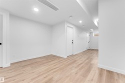 Spacious interior featuring light wood-finish flooring, white walls, recessed lighting, and white baseboards - 