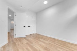 Room featuring wood-finish flooring, recessed lighting, white walls, and contemporary doors with matte black hardware - 