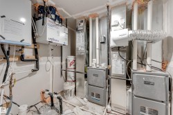 Mechanical room featuring multiple furnaces, a hot water heater, and a Lifebreath air exchanger - 