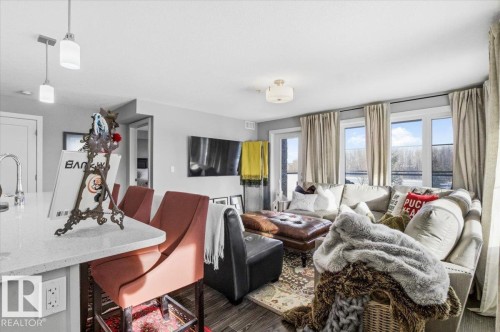 This inviting living space features light gray walls, recessed lighting, and large windows with privacy drapes, offering natural light - 211 5029 Edgemont Boulevard, Edmonton, AB - Indoor