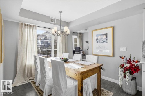 Dining area featuring hardwood floors, a large window with draped curtains, and a chandelier - 211 5029 Edgemont Boulevard, Edmonton, AB - Indoor Photo Showing Dining Room