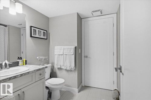 Bathroom featuring a vanity with an undermount sink, granite countertop, and mosaic tile backsplash - 211 5029 Edgemont Boulevard, Edmonton, AB - Indoor Photo Showing Bathroom