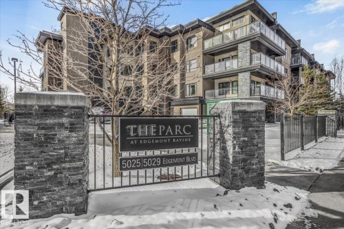 The property features a multi-story building with balconies, glass railings, and stone accents - 211 5029 Edgemont Boulevard, Edmonton, AB - Outdoor With Balcony