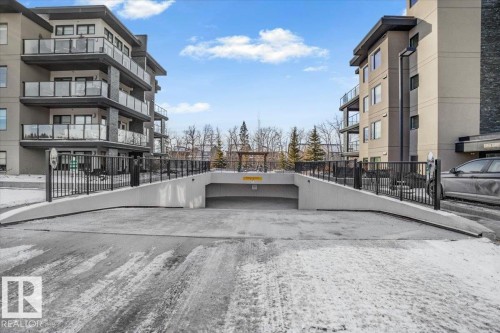 The property features a dedicated underground parking entrance, with two multi-story buildings visible - 211 5029 Edgemont Boulevard, Edmonton, AB - Outdoor With Balcony