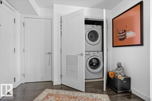Convenient laundry area featuring a stacked washer and dryer, discreetly located within a white bi-fold door closet - 211 5029 Edgemont Boulevard, Edmonton, AB - Indoor Photo Showing Laundry Room