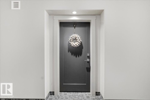The property features a modern dark gray entrance door with white trim, complemented by a recessed light overhead - 211 5029 Edgemont Boulevard, Edmonton, AB -  Photo Showing Other Room