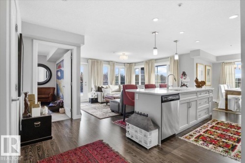 The property features an open-concept living area with dark hardwood flooring and light-colored walls - 211 5029 Edgemont Boulevard, Edmonton, AB - Indoor