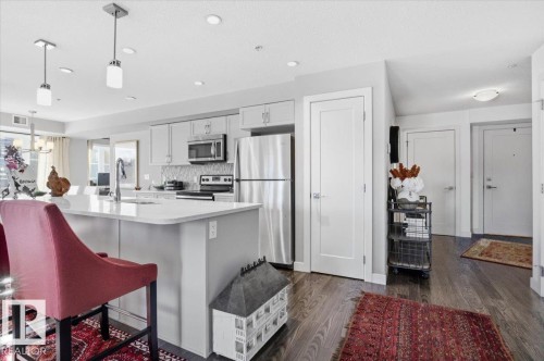 The kitchen features light-colored cabinetry, stainless steel appliances, and a central island with a sink and a light-colored countertop - 211 5029 Edgemont Boulevard, Edmonton, AB - Indoor Photo Showing Kitchen With Upgraded Kitchen