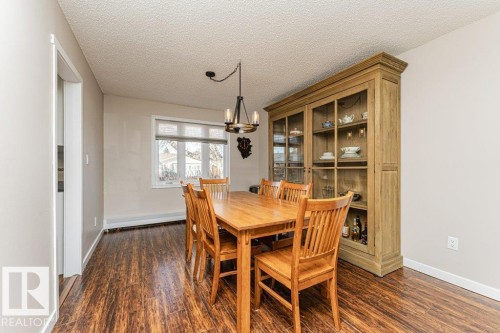 Dining area featuring wood-finish flooring, a contemporary chandelier, a window with blinds, and light-colored wall paint - 1727 65 Street, Edmonton, AB - Indoor Photo Showing Dining Room