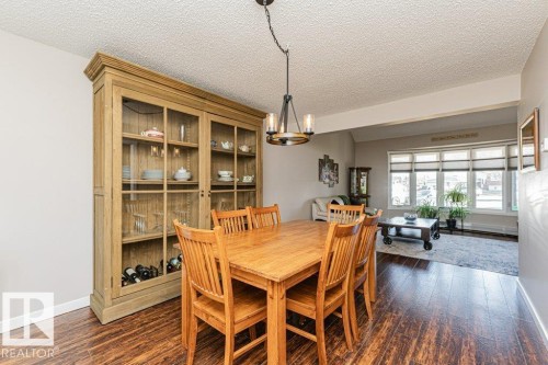 Open-concept dining area with wood-finish flooring, a contemporary chandelier, and direct sightlines to the living space - 1727 65 Street, Edmonton, AB - Indoor Photo Showing Dining Room