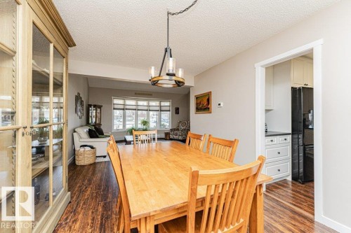 Open-concept dining area featuring wood-finish flooring, a contemporary chandelier, and light gray wall paint - 1727 65 Street, Edmonton, AB - Indoor Photo Showing Dining Room