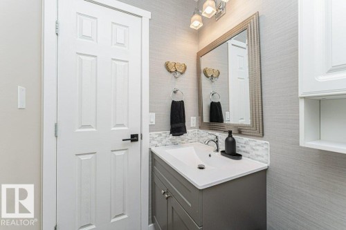 Bathroom vanity featuring a white countertop with integrated sink, gray cabinetry, and mosaic tile backsplash - 1727 65 Street, Edmonton, AB - Indoor Photo Showing Bathroom
