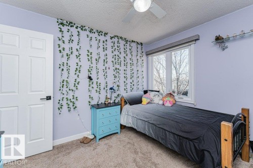 Bedroom featuring broadloom carpet, a ceiling fan, a window with exterior views, and a white six-panel door with black hardware - 1727 65 Street, Edmonton, AB - Indoor Photo Showing Bedroom