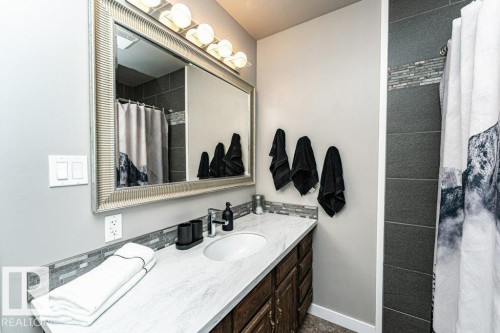 Bathroom featuring a large vanity with a single basin sink, light-toned countertop, and dark wood-finish cabinetry - 1727 65 Street, Edmonton, AB - Indoor Photo Showing Bathroom
