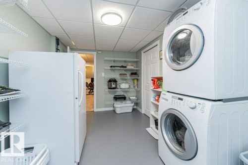 Laundry area featuring a stacked washer and dryer, painted flooring, white walls, and a drop ceiling - 1727 65 Street, Edmonton, AB - Indoor Photo Showing Laundry Room