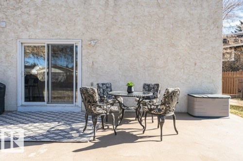 Private concrete patio featuring a textured stucco exterior and a large glass sliding door - 1727 65 Street, Edmonton, AB - Outdoor