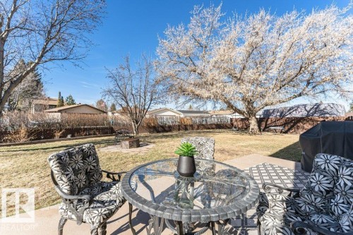 Expansive backyard featuring a concrete patio, mature deciduous trees, a fire pit, and a fenced perimeter - 1727 65 Street, Edmonton, AB - Outdoor