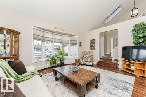 Living area featuring high vaulted ceilings, wood-finish flooring, and a multi-pane bay window - 1727 65 Street, Edmonton, AB - Indoor Photo Showing Living Room