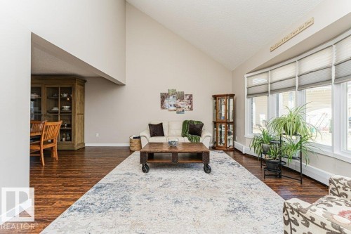 Spacious living area featuring high vaulted ceilings, multiple large windows with horizontal blinds, and rich wood-finish flooring - 1727 65 Street, Edmonton, AB - Indoor Photo Showing Living Room