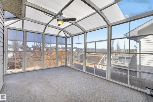Sunroom featuring a vaulted translucent ceiling, full-height windows, light-toned textured flooring, a ceiling fan with integrated lighting, and white horizontal siding - 720 87 Street, Edmonton, AB -  Photo Showing Other Room