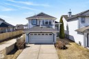 Two-story residence featuring light blue siding with dark trim accents, an attached garage with translucent panel windows, and a concrete driveway - 720 87 Street, Edmonton, AB  - Outdoor 
