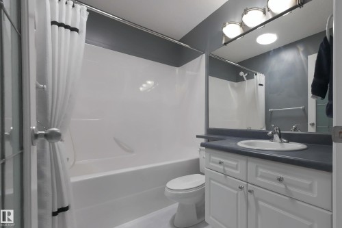 Full bathroom featuring a white vanity with cabinet storage, a dark countertop, a white drop-in sink, and a shower-bathtub combination with a white surround - 720 87 Street, Edmonton, AB - Indoor Photo Showing Bathroom