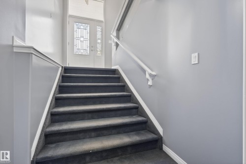 Staircase with dark gray carpeted treads, white risers, and white trim - 720 87 Street, Edmonton, AB - Indoor Photo Showing Other Room