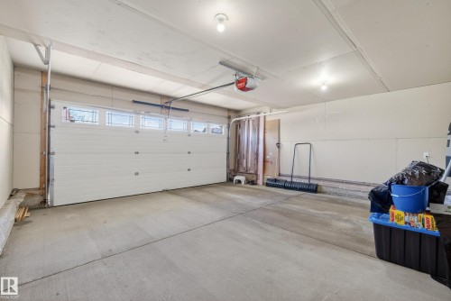Attached garage featuring a sectional door with frosted lites, concrete flooring, and exposed ceiling joists - 720 87 Street, Edmonton, AB - Indoor Photo Showing Garage