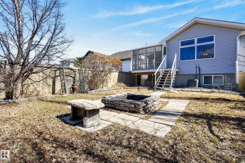 Expansive backyard featuring a stone-lined fire pit, a natural stone bench, and a paved pathway - 720 87 Street, Edmonton, AB - Outdoor