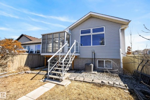 Rear exterior featuring a screened-in porch, deck with white railings and stairs, and a concrete pathway - 720 87 Street, Edmonton, AB - Outdoor