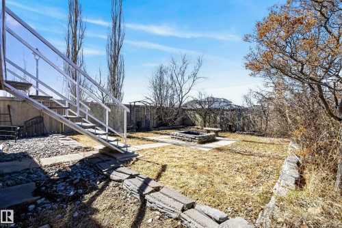 Expansive backyard featuring a stone fire pit area, concrete stepping stones, and a metal exterior staircase - 720 87 Street, Edmonton, AB - Outdoor With View