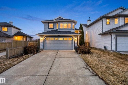 Two-story home featuring light blue siding, dark trim, an attached two-car garage, and a bay window - 720 87 Street, Edmonton, AB - Outdoor