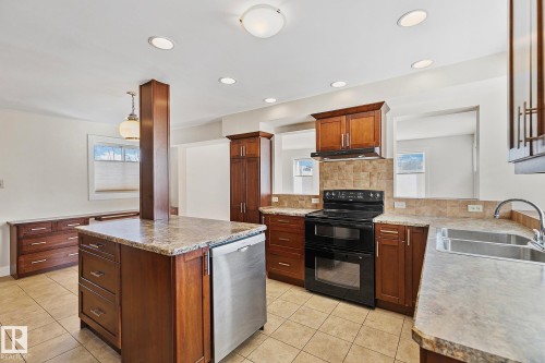 The kitchen features an island with a stainless steel dishwasher, tile flooring, and recessed lighting - 10823 130 Street, Edmonton, AB - Indoor Photo Showing Kitchen With Double Sink