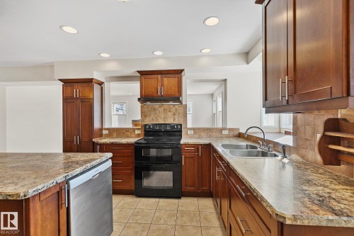 The kitchen features granite countertops, dark wood cabinetry, and a double basin sink - 10823 130 Street, Edmonton, AB - Indoor Photo Showing Kitchen With Double Sink