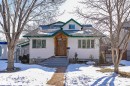 The property features white siding, a green roof, and a prominent wooden front door with an overhang - 10823 130 Street, Edmonton, AB  - Outdoor 