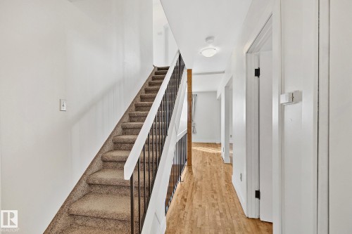 Hallway featuring a staircase with carpeted treads and a black metal railing - 10823 130 Street, Edmonton, AB - Indoor Photo Showing Other Room