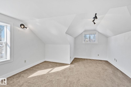 This space features neutral-toned carpeting, white walls, and two windows providing natural light - 10823 130 Street, Edmonton, AB - Indoor Photo Showing Other Room