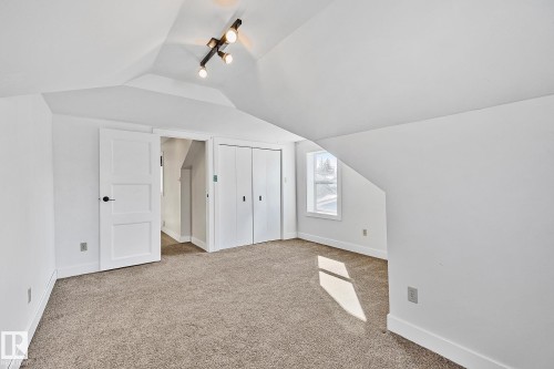 This versatile room features neutral carpeting, white walls, and a window providing natural light - 10823 130 Street, Edmonton, AB - Indoor Photo Showing Other Room