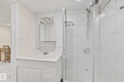 Bathroom featuring a white vanity with an integrated sink, a mirrored medicine cabinet, and a tiled shower enclosure with a glass door - 10823 130 Street, Edmonton, AB - Indoor Photo Showing Bathroom