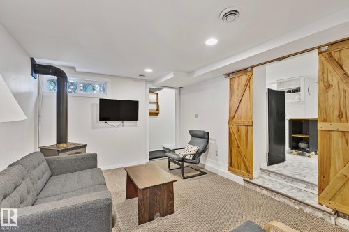 Living area featuring a freestanding stove, a window, and wood barn doors - 10823 130 Street, Edmonton, AB - Indoor