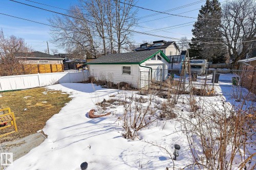 The property includes a detached garage with a green roof, a fenced yard, and a white privacy fence - 10823 130 Street, Edmonton, AB - Outdoor
