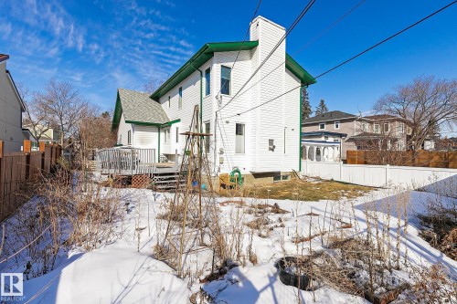The property features a multi-level wooden deck and a white exterior with green trim - 10823 130 Street, Edmonton, AB - Outdoor With Deck Patio Veranda