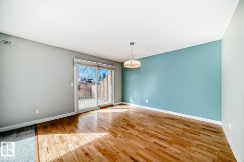 Wood-finish flooring throughout, complemented by a contemporary ceiling light fixture - 2709 124 Street, Edmonton, AB - Indoor Photo Showing Other Room