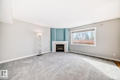 Corner fireplace with a classic white mantel - 2709 124 Street, Edmonton, AB - Indoor Photo Showing Other Room With Fireplace